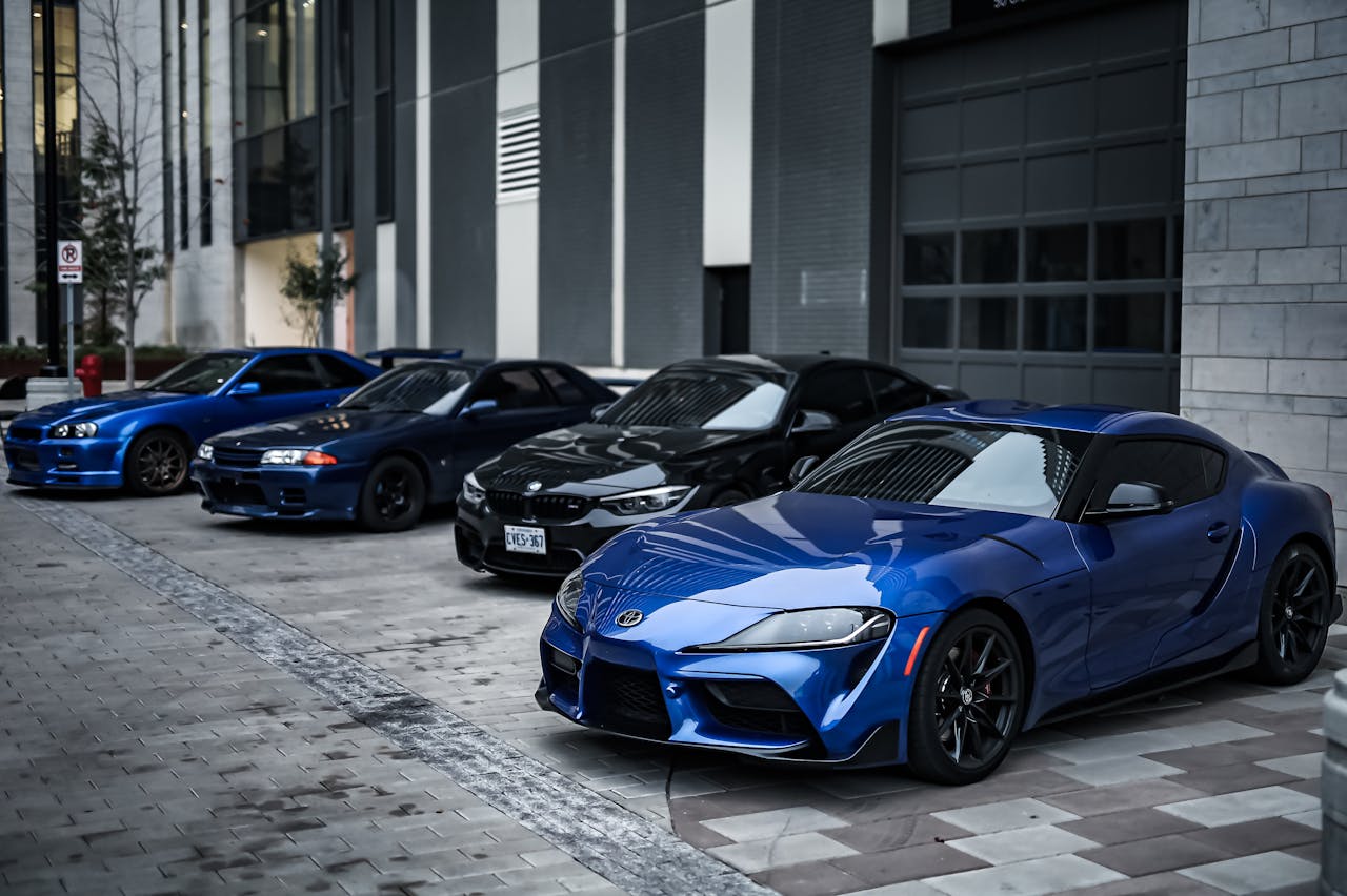 Line-up of sleek sports cars parked outside a modern dealership showcasing automotive styling.